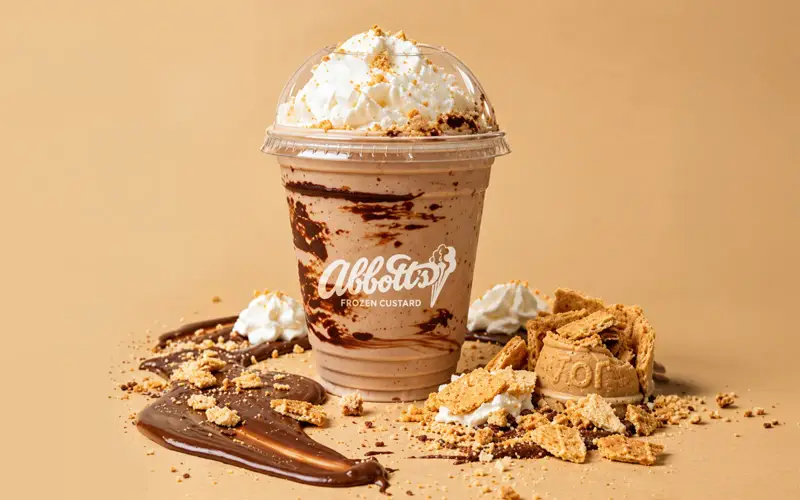 Chocolate frozen custard shake topped with whipped cream and crushed cookie, with the Abbott's Frozen Custard logo on the cup